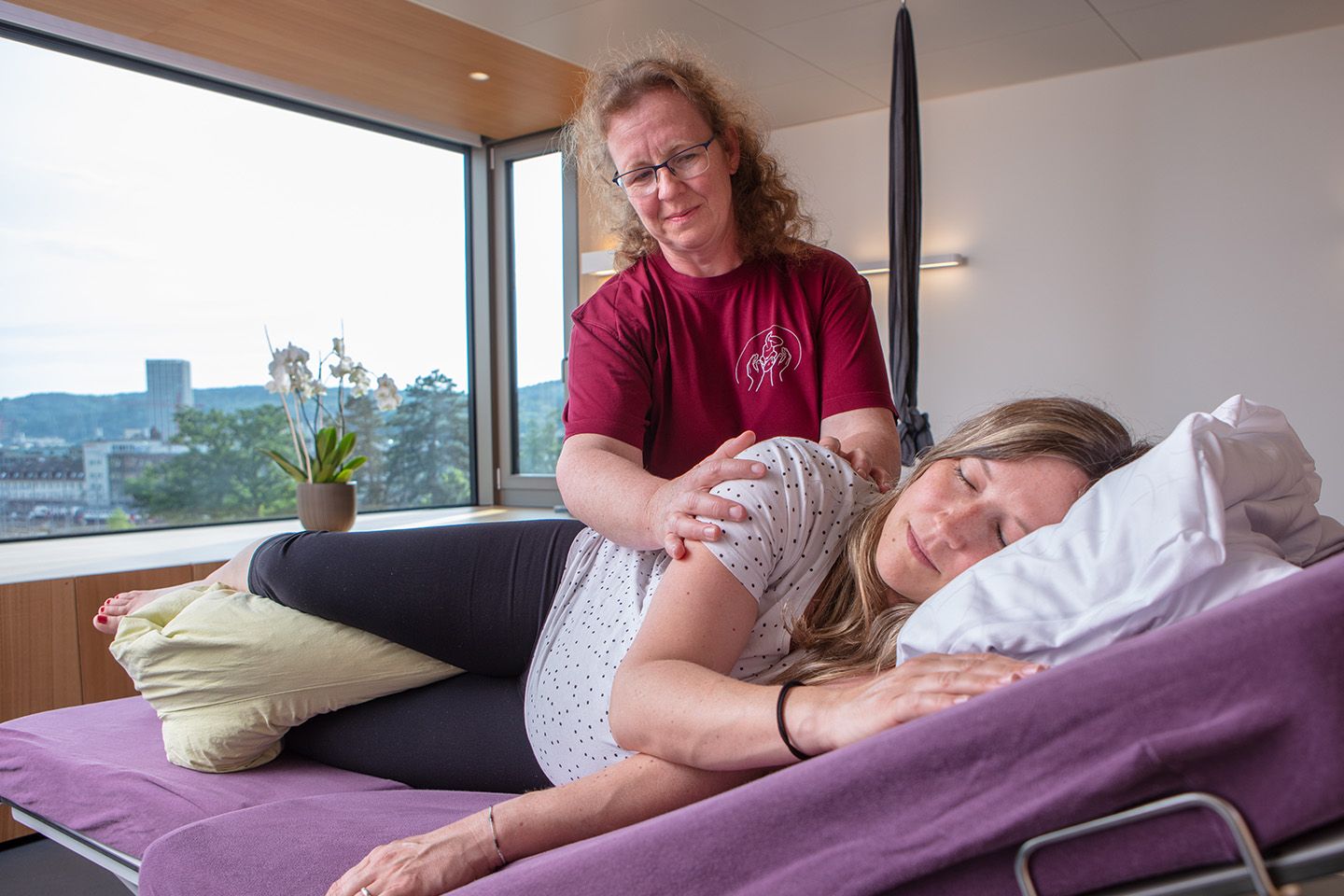 Therapeutin mit einer schwangeren Frau bei der Craniosacraltherapie. Die Craniosacraltherapie ist eine sanfte Methode zur Förderung des Wohlbefindens.