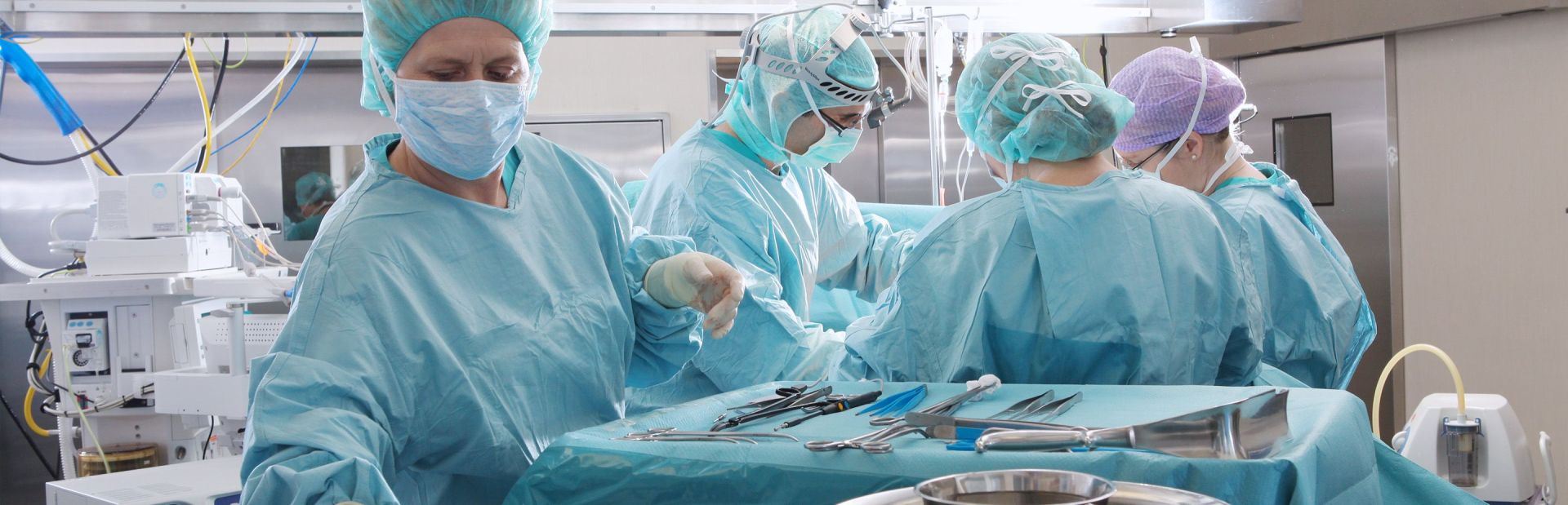 Vier Chirurgen operieren eine Patient:in.