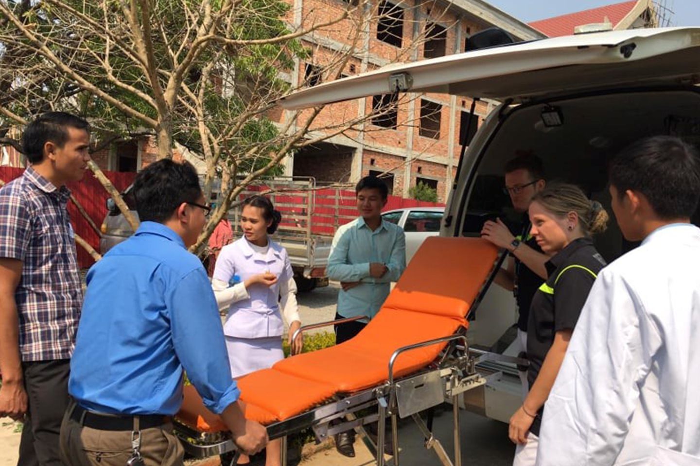 7 Personen stehen vor einem Rettungsfahrzeug in Laos